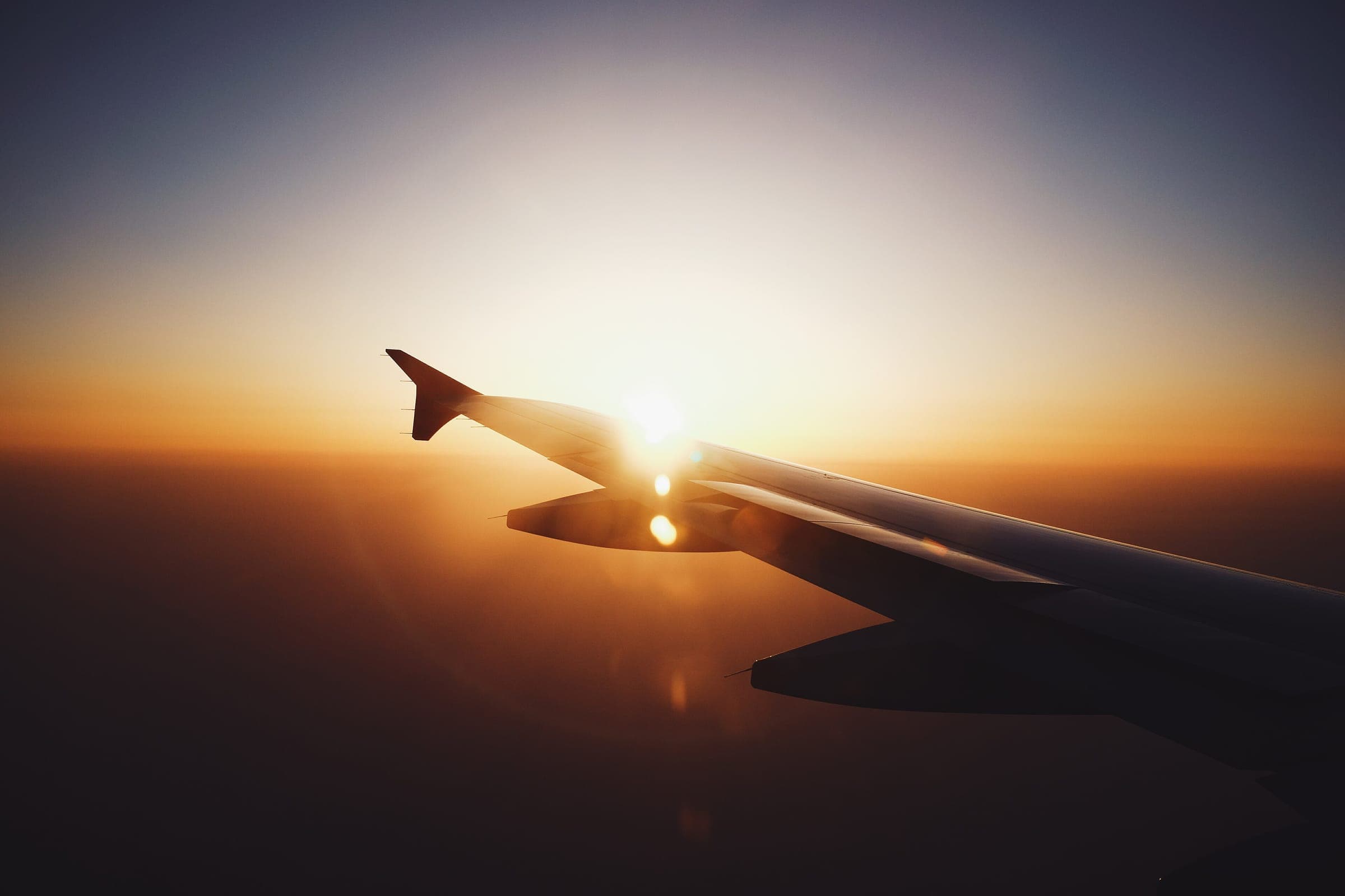 Ala del avión vista desde la ventanilla con el sol en el horizonte