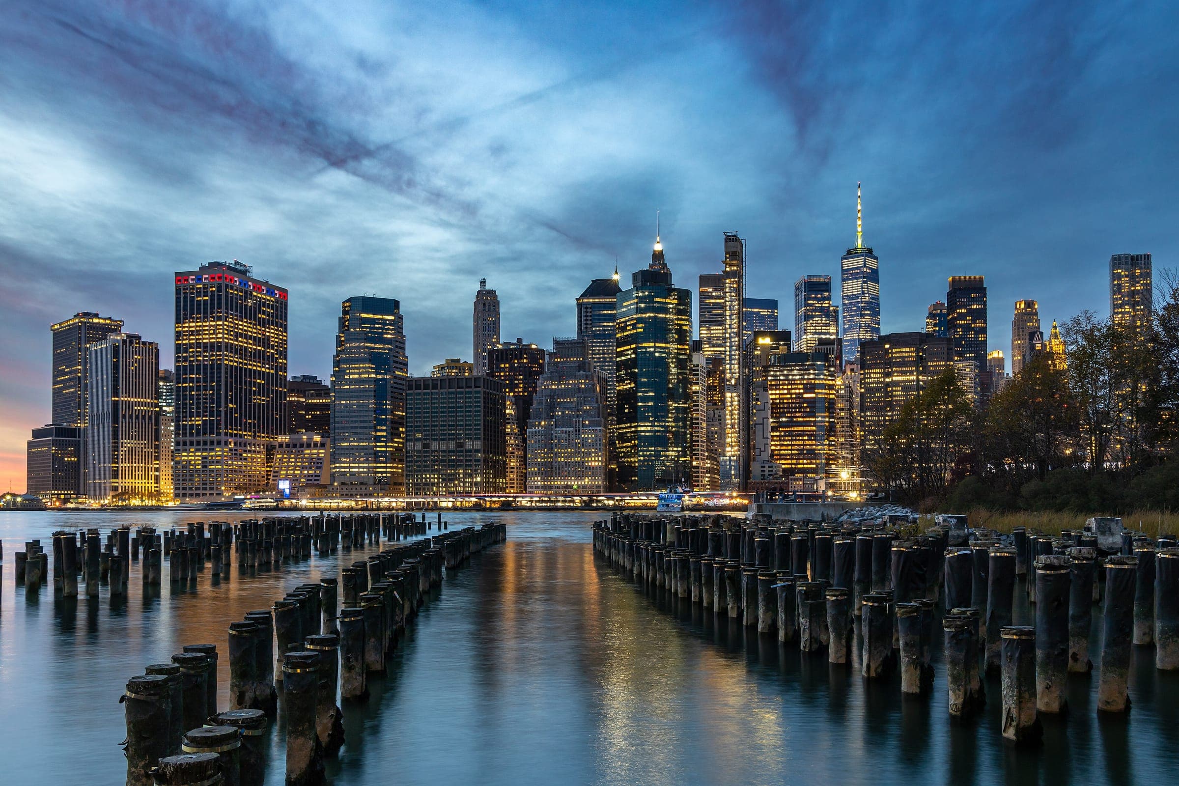 El sur de Manhattan iluminado en la hora azul sobre los pilotes del muelle