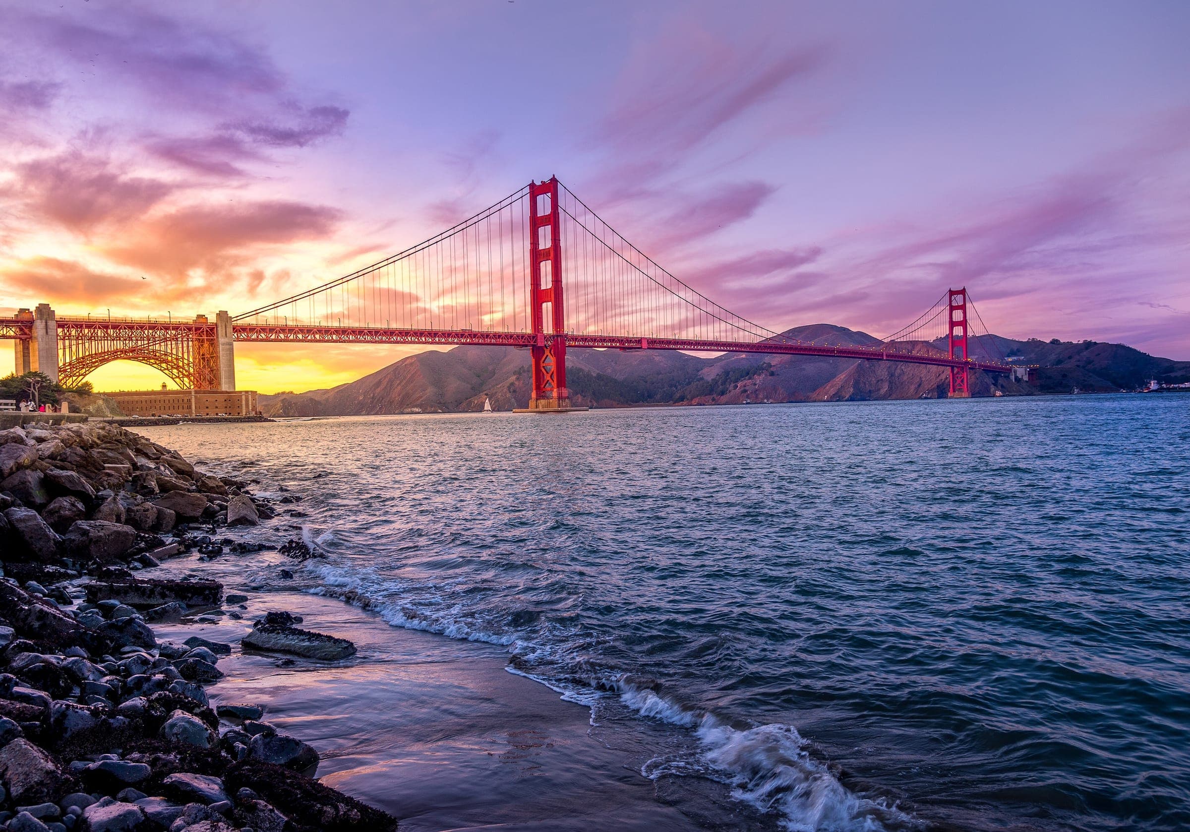 Puente Golden Gate bajo un atardecer morado y dorado, San Francisco